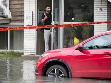 a resident stands in a doorway beside a flooded street