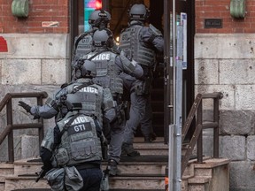 Police wearing tactical gear file into a building