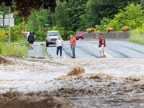 people stand near a washed out road