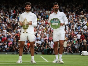 Male tennis players stand on grass with their prizes