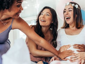 emale friends touching pregnant woman's belly at baby shower party