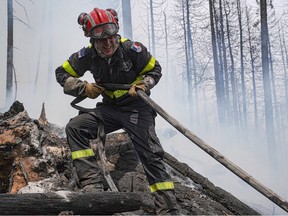 This June 28, 2023, image released by the Société de protection des forets (SOPFEU) on June 30, 2023, shows a French firefighter assisting with wildfires at Lac Larouche.