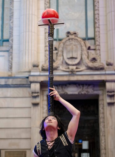 A performer balances a ball on a long stand placed on his forehead