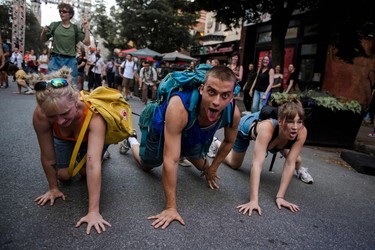 Three circus performers pretend to be dogs on a street