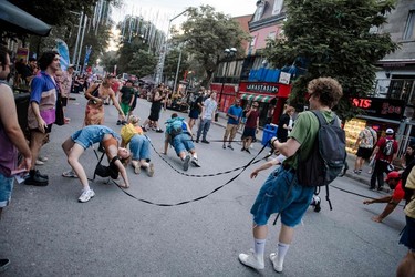 A man walks three circus performers pretending to be dogs down a street
