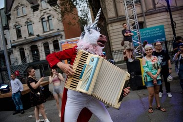 A person dressed as a unicorn plays the accordion