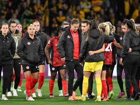 Canadian women's soccer players look sad wearing jackets on the pitch