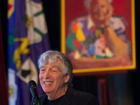 Roch Carrier at a microphone in front of a painting of May Cutler