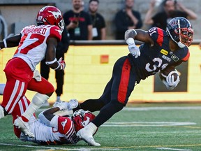 Alouettes running-back William Stanback is tackled by Stampeders' Kobe Williams.