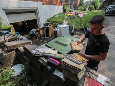 two men try to clean flood-damaged items outside
