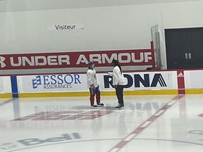 Two men seen from a distance talking on an ice rink