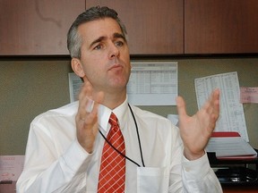 Bill Majcher in shirt and tie gestures in an office