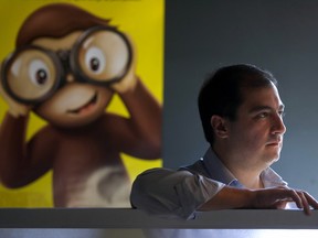 Francisco Del Cueto in a dark room with a poster of an animated monkey