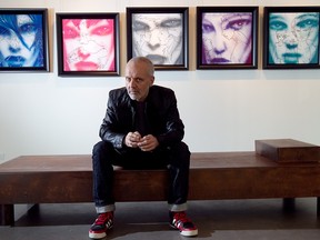 A men sits on a bench in front of a row of framed works in an art gallery