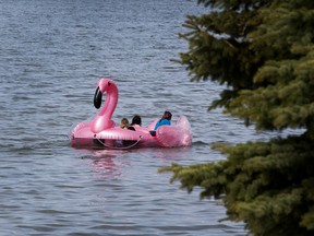 A giant inflatable pink flamingo with three people aboard
