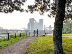a couple walks on a footpath with the five roses building smoggy in the background