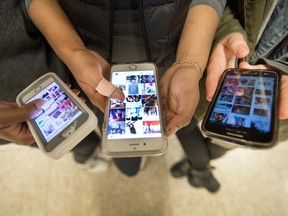 photo shows the hands of three teenagers holding smartphones