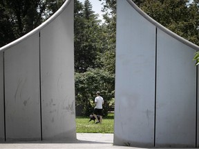 a man is seen walking a dog through a sculpture that looks like a rounded gate