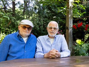 Two men sit behind a table in a garden