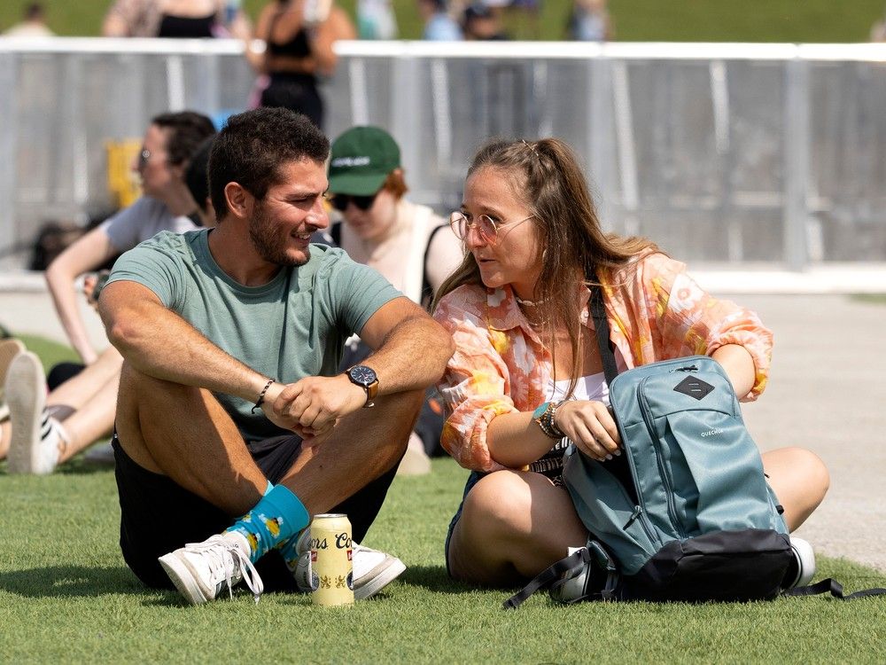 A couple sit on the grass in the sun