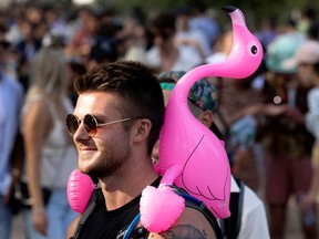 A man walks at osheaga with an inflatable pink flamingo on his shoulders