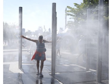 A woman walks through the misting station at Osheaga in Montreal on Sunday, Aug. 6, 2023.