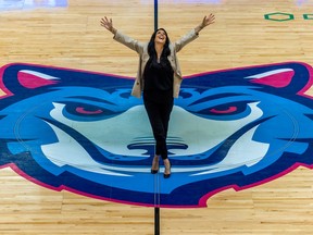 Annie Larouche raises her arms in the air standing at the centre of the Montreal Alliance basketball court