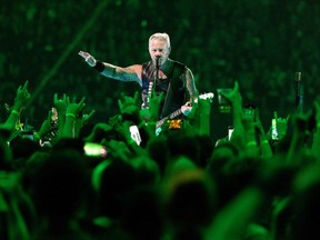 James Hetfield of Metallica seen performing through a sea of fans giving devil horn gestures