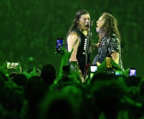 Robert Trujillo and Kirk Hammett sing into the same mic during a Metallica concert