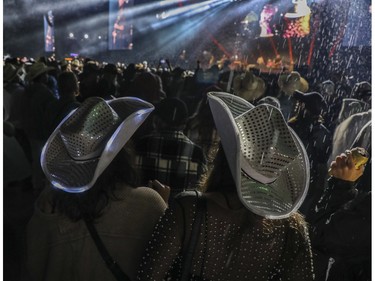 People stand in the rain as they listen to the Brothers Osborne perform at the Lasso country-music festival at Parc Jean-Drapeau in Montreal on Saturday, Aug. 19, 2023.