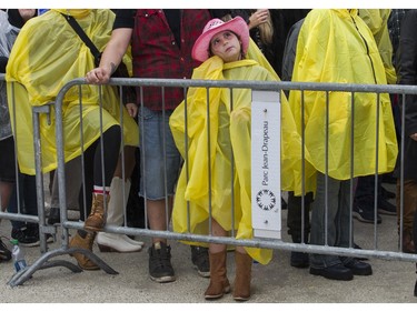 A youngster is covered up for the rain at the Lasso country-music festival at Parc Jean-Drapeau in Montreal on Saturday, Aug. 19, 2023.