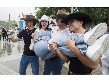 Katie Ferguson is held by strangers Anthony Jutras, Émile Dumont and Mathieu Caron as she was being photographed and fêted by friends for her bachelorette party at the Lasso country-music festival at Parc Jean-Drapeau in Montreal on Saturday, Aug. 19, 2023.