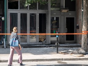 A person walking by the police tape blocking off a fire-damaged building