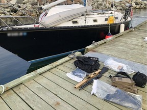 Firearms and ammunition on a dock beside a sailboat in Gaspesie
