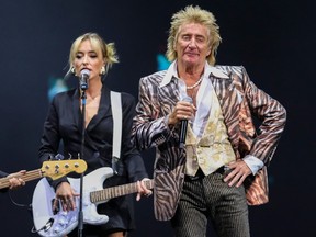 Rod Stewart poses in front of a female guitarist