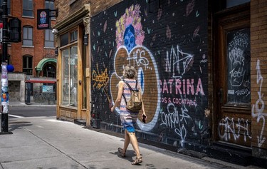A woman walks past a mural on the wall of restaurant La Catrina on St-Viateur. Graffiti tags now cover it.
