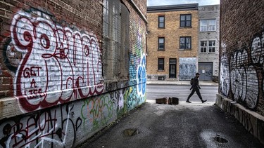 A man walks by ggraffiti-filled alley next to the former Baron Byng High School on St-Urbain St.