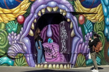 Shana Nirmala poses for Quentin Fourie in front of a purple-tinged mural of a gaping mouth on a building on St-Laurent Blvd. and Marie-Anne St.