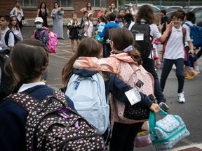 Two students hug in a crowded schoolyard