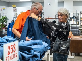 Joanne Côté holds a shirt against Michel Côté while glancing at other clothing.