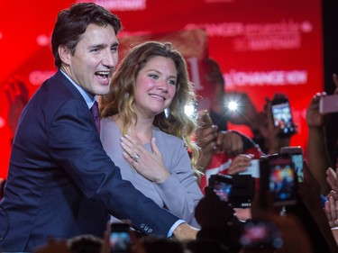 Justin Trudeau extends a hand to supporters as Sophie Grégoire Trudeau places her hand over her chest in a crowd of people holding cellphones
