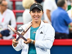 A woman holds a trophy after a tennis tournament