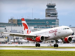 An Air Canada Rouge jet lands with the terminal in the backgriound