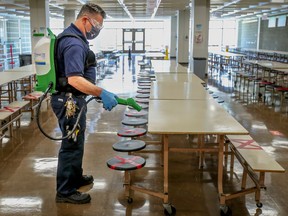 A caretaker disinfects tables in the cafeteria at John F. Kennedy High School in Montreal in 2020.