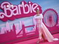 margot robbie in a pink dress in front of a barbie logo