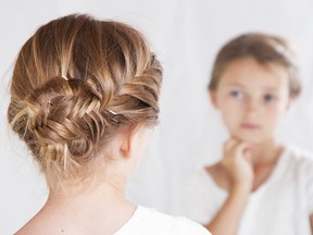 child with a brain stares at herself in the mirror