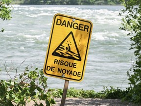 A sign that translates to "risk of drowning," is shown next to the St. Lawrence River in Montreal on June 26, 2023. It has been a particularly deadly year on the water in Quebec, which so far accounts for more than one-third of all drownings reported in the country.