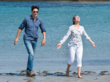 Prime Minister Justin Trudeau and Sophie Grégoire Trudeau walk on the beach, as Grégoire Trudeau looks to the sky with arms stretched