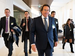 Pierre Karl Péladeau walks along a hallway with a group of people following him