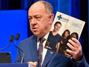 Christian Dubé holds a book with his health reform plan